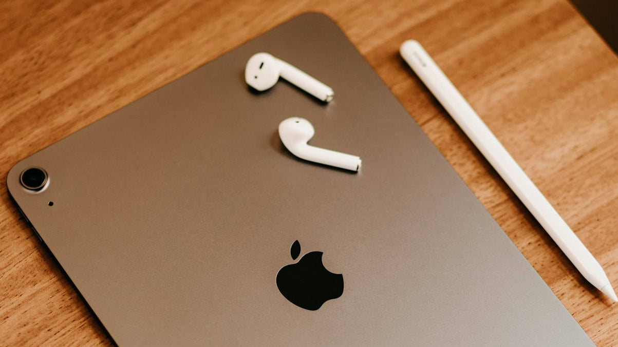 Space gray iPad with AirPods and Apple Pencil