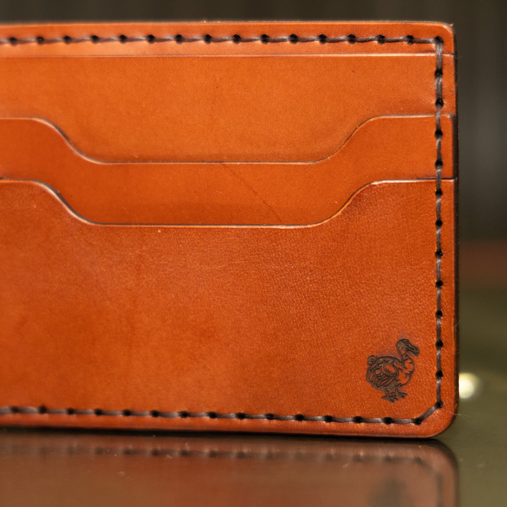 Close-up of saddle stitching and dodo stamp on English Bridle leather bifold wallet