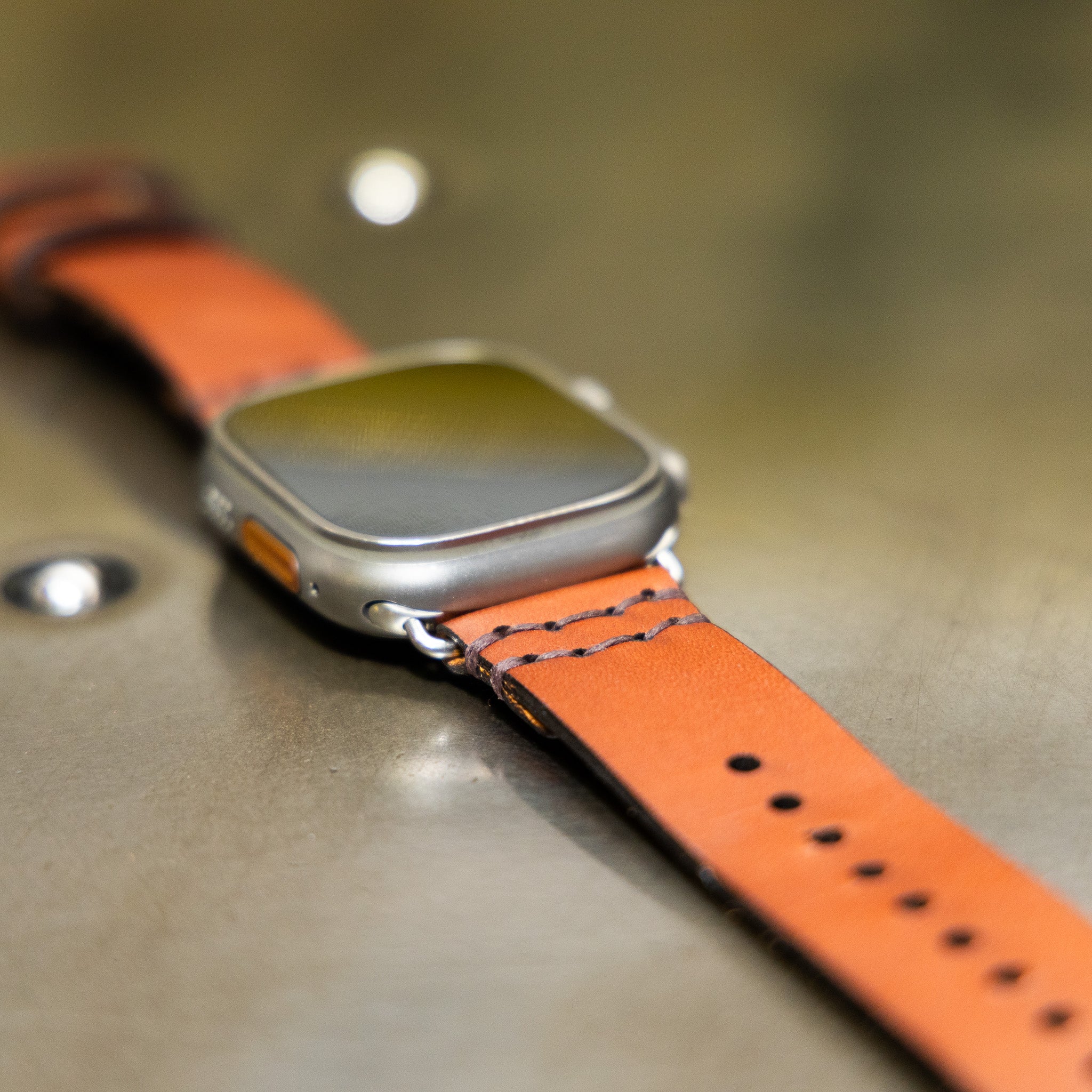 Tan leather Apple Watch band with polished steel buckle and adapters