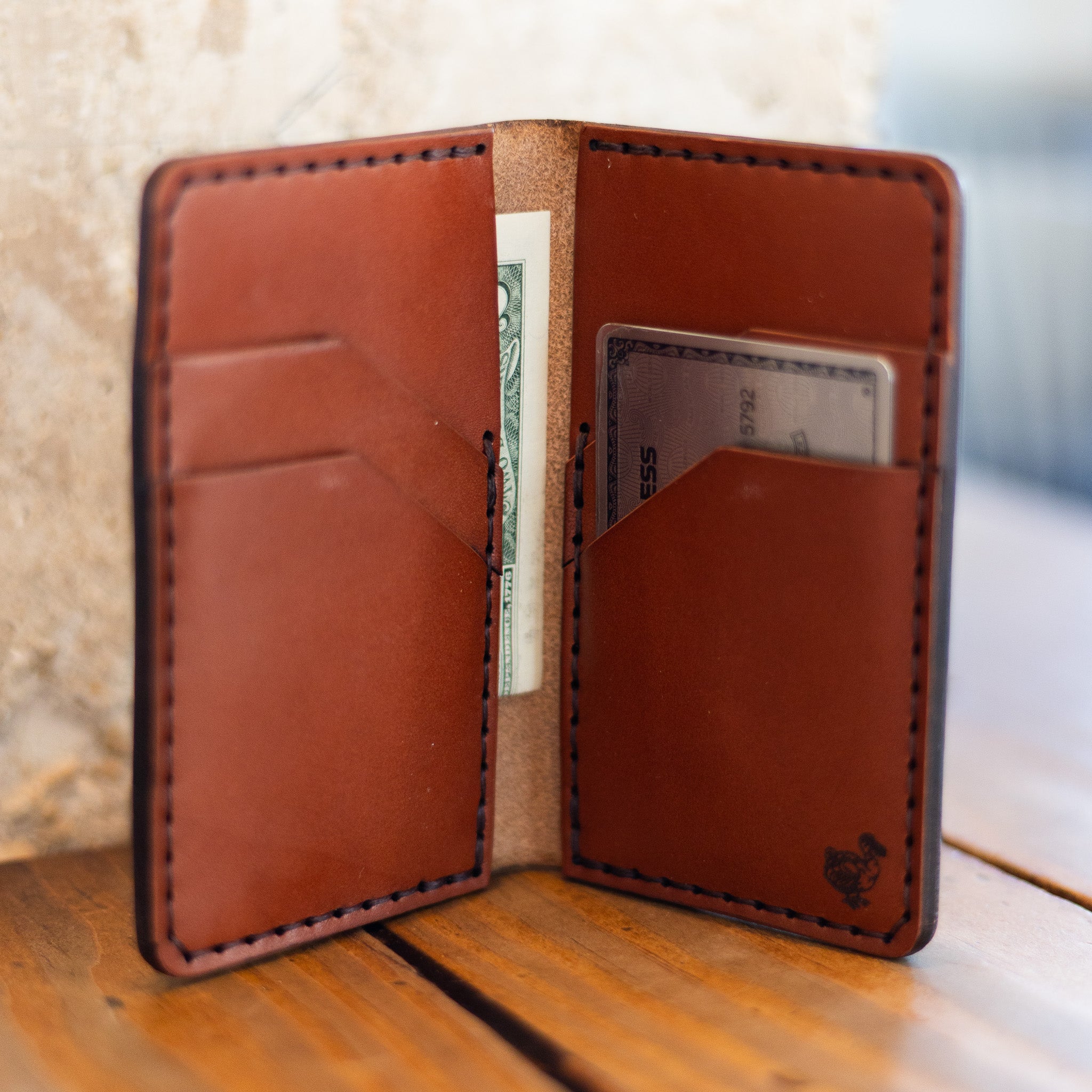 Vertical bifold wallet open like a book with cash and card, lifestyle shot