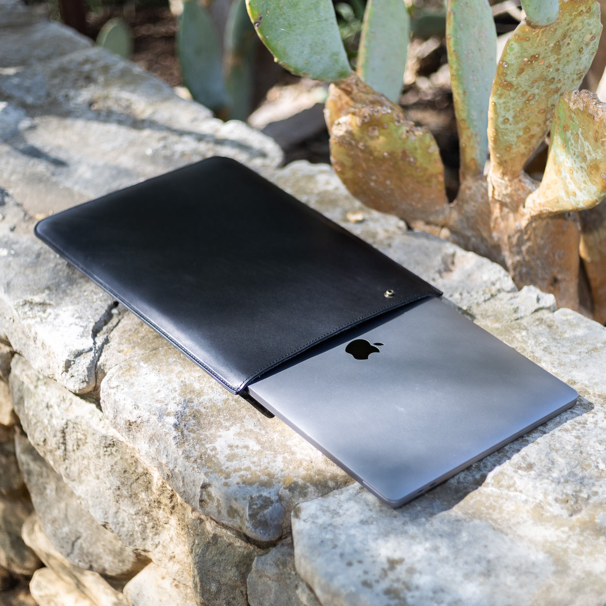 Black leather MacBook sleeve with a MacBook Pro sliding out