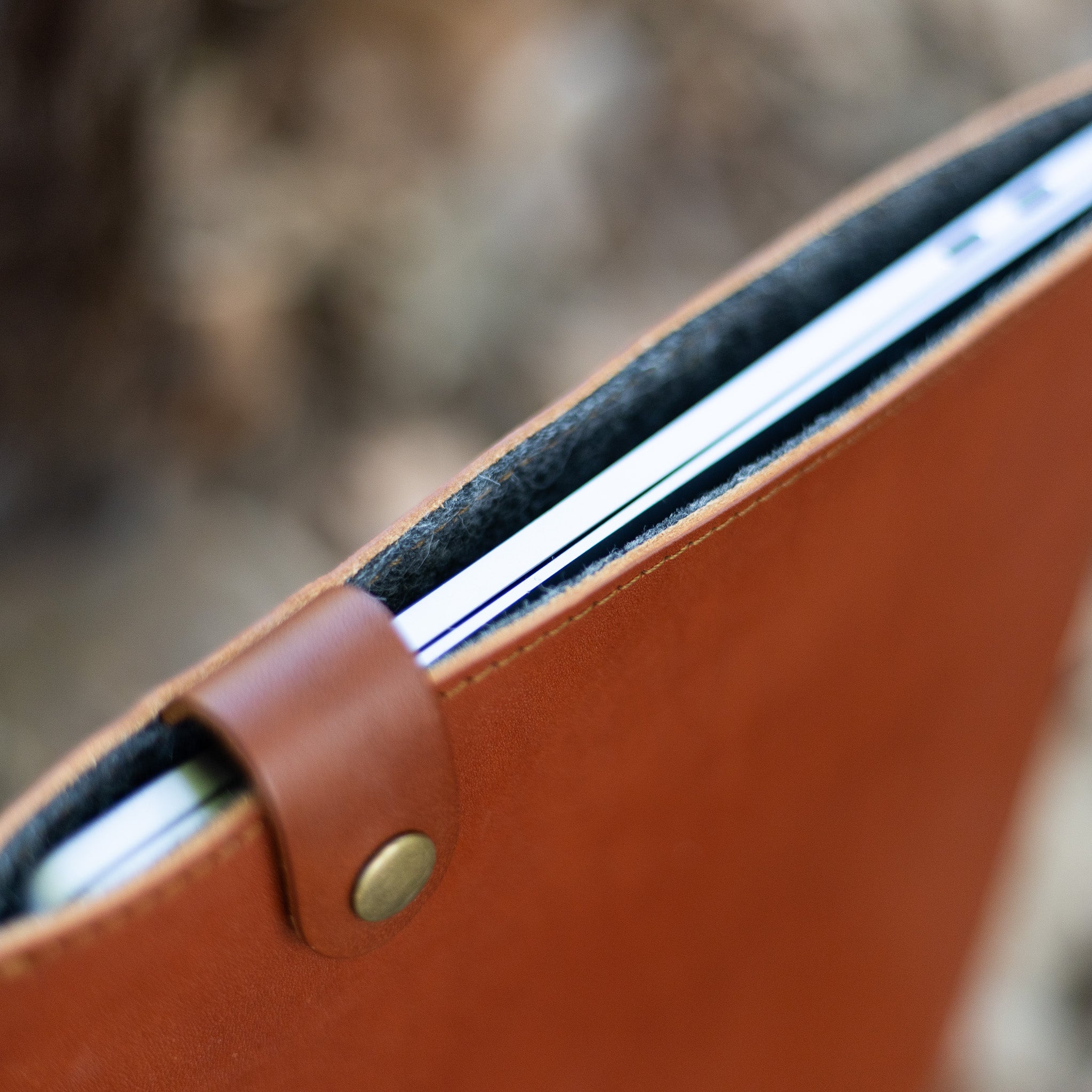 MacBook seated in a wool-lined leather sleeve with the snap tab open