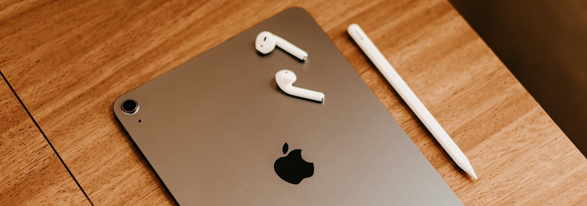 Space gray iPad with AirPods and Apple Pencil