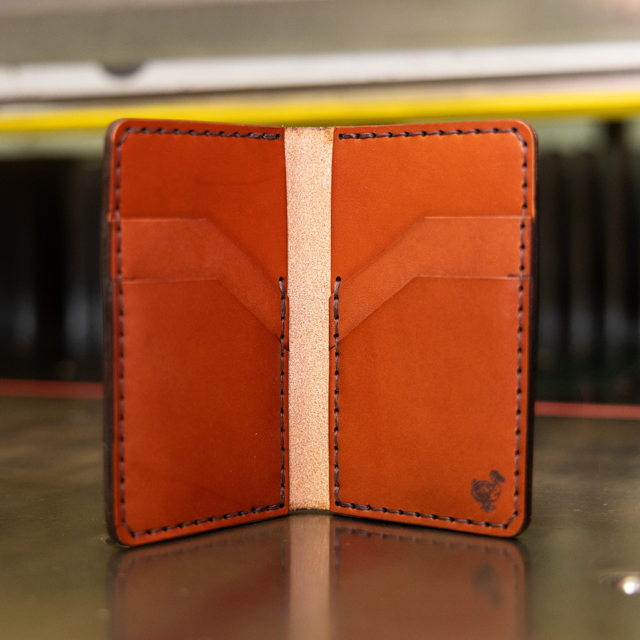 Vertical bifold wallet in chestnut English Bridle leather standing open like a book, handmade in USA