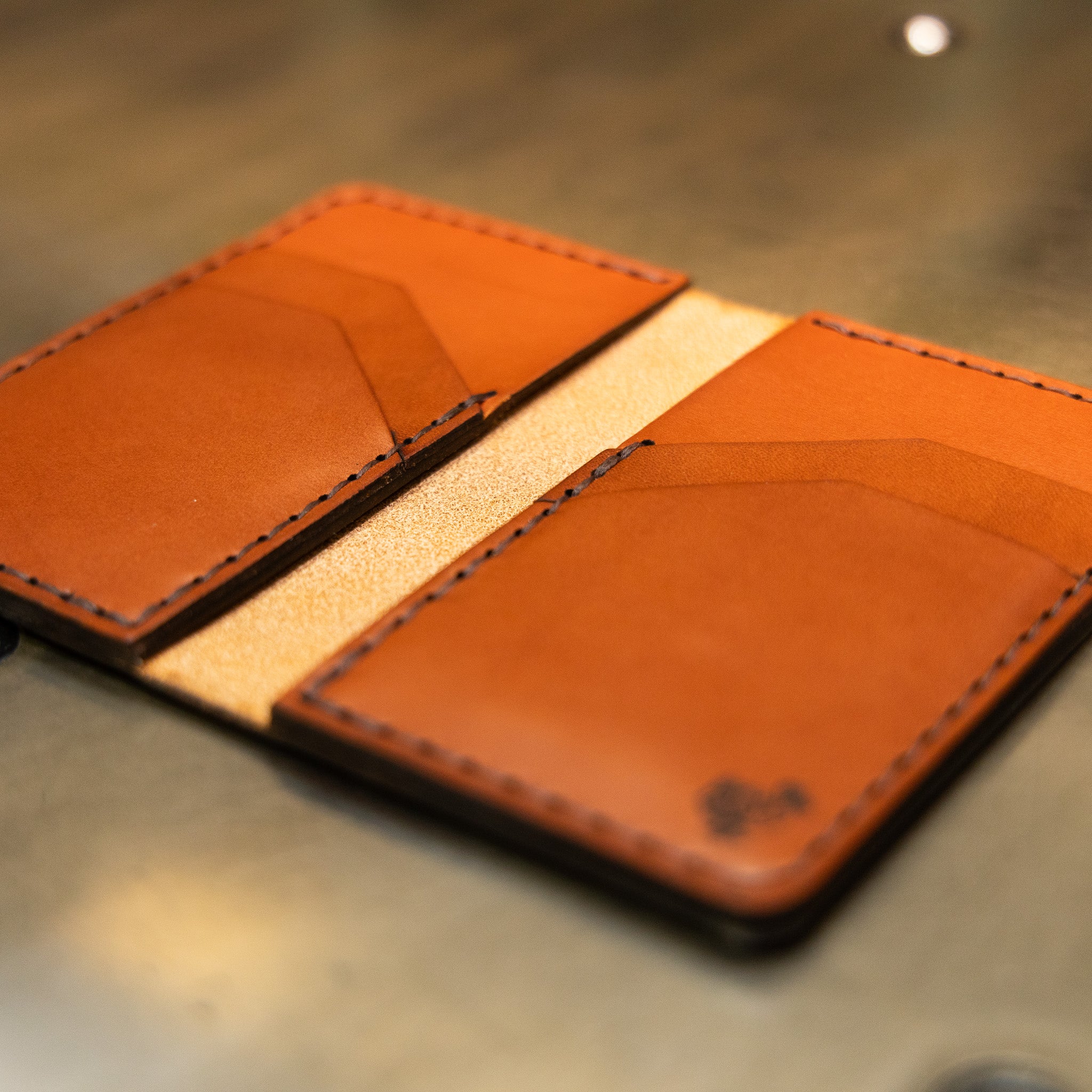 Vertical leather wallet lying open, saddle stitched English Bridle panels