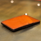 Slim leather front pocket wallet lying flat, four card pockets with angled quick-draw slots