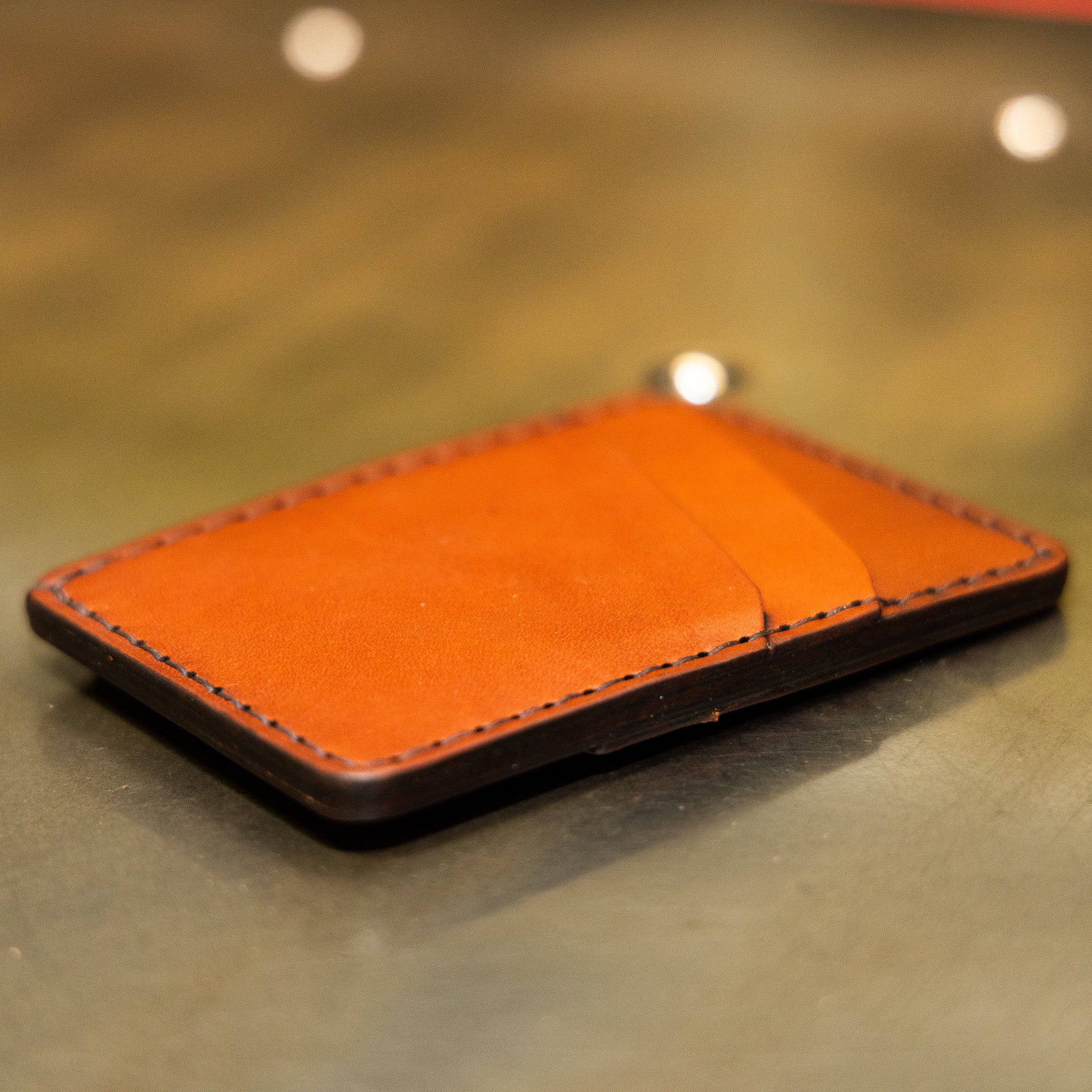 Slim leather front pocket wallet lying flat, four card pockets with angled quick-draw slots