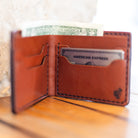 Handmade bifold wallet standing open with cash and cards in use