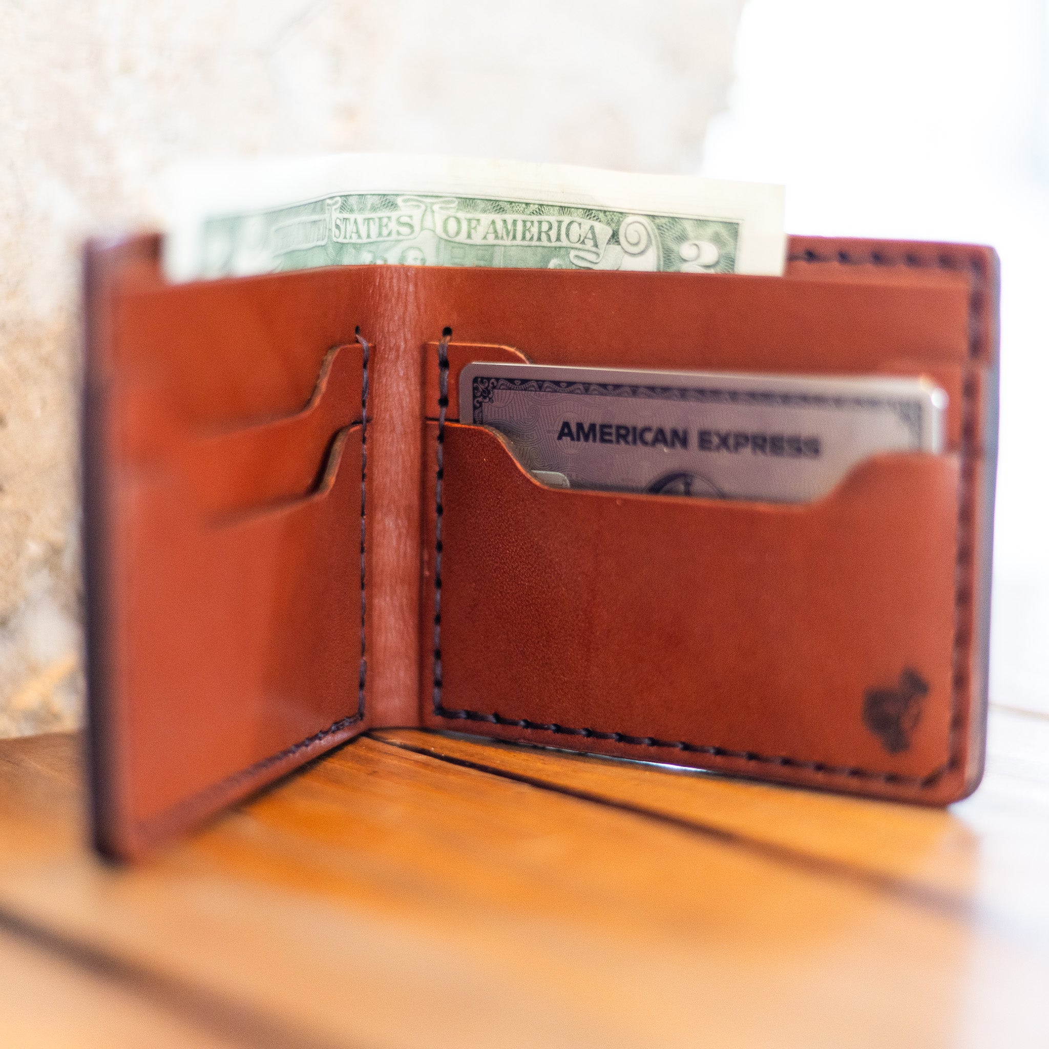 Handmade bifold wallet standing open with cash and cards in use