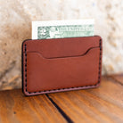 Slim leather card holder with cash, lifestyle shot on wood table