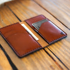 Vertical leather wallet lying open on wood table showing card pockets