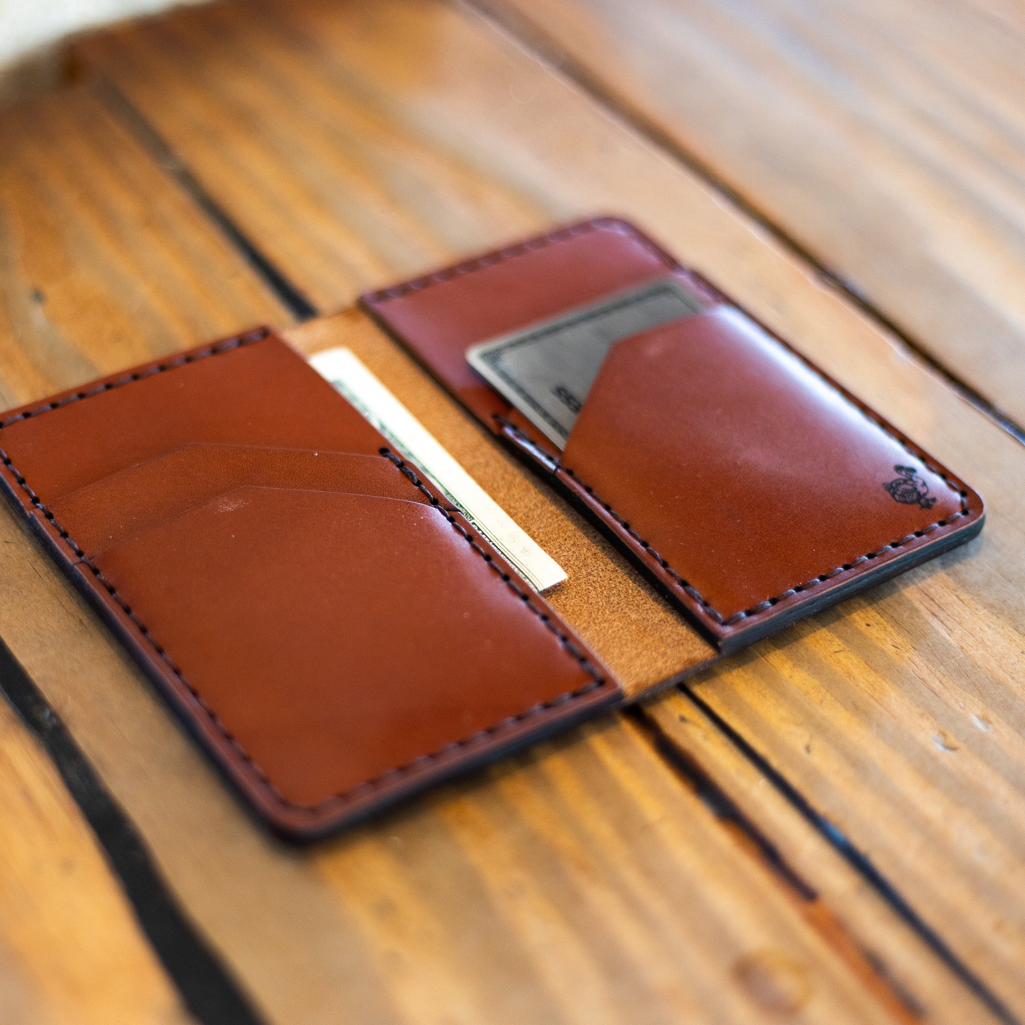 Vertical leather wallet lying open on wood table showing card pockets