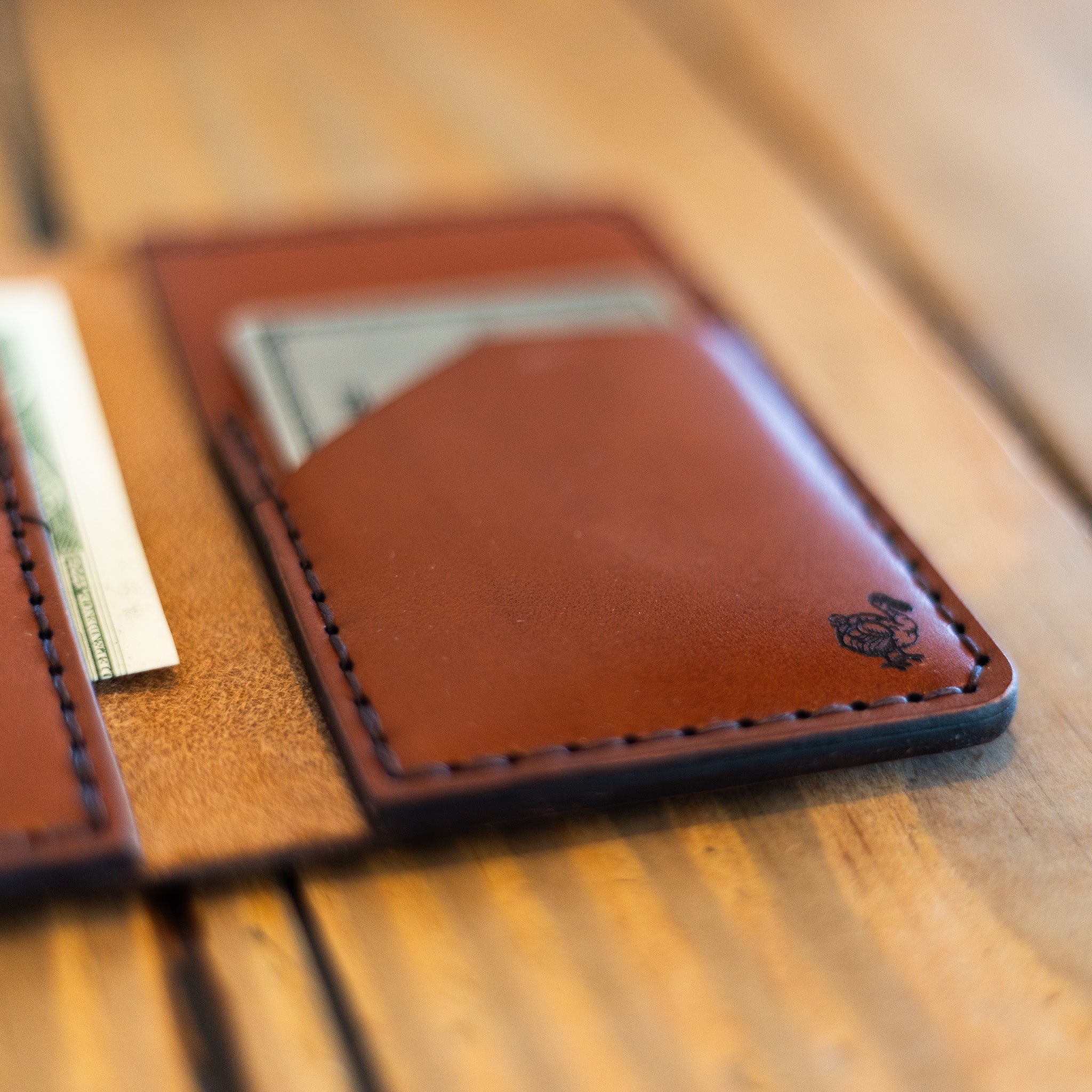 Close-up of slim leather card holder with dodo stamp and saddle stitching
