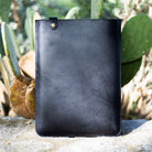 Black English Bridle leather MacBook sleeve propped against cactus