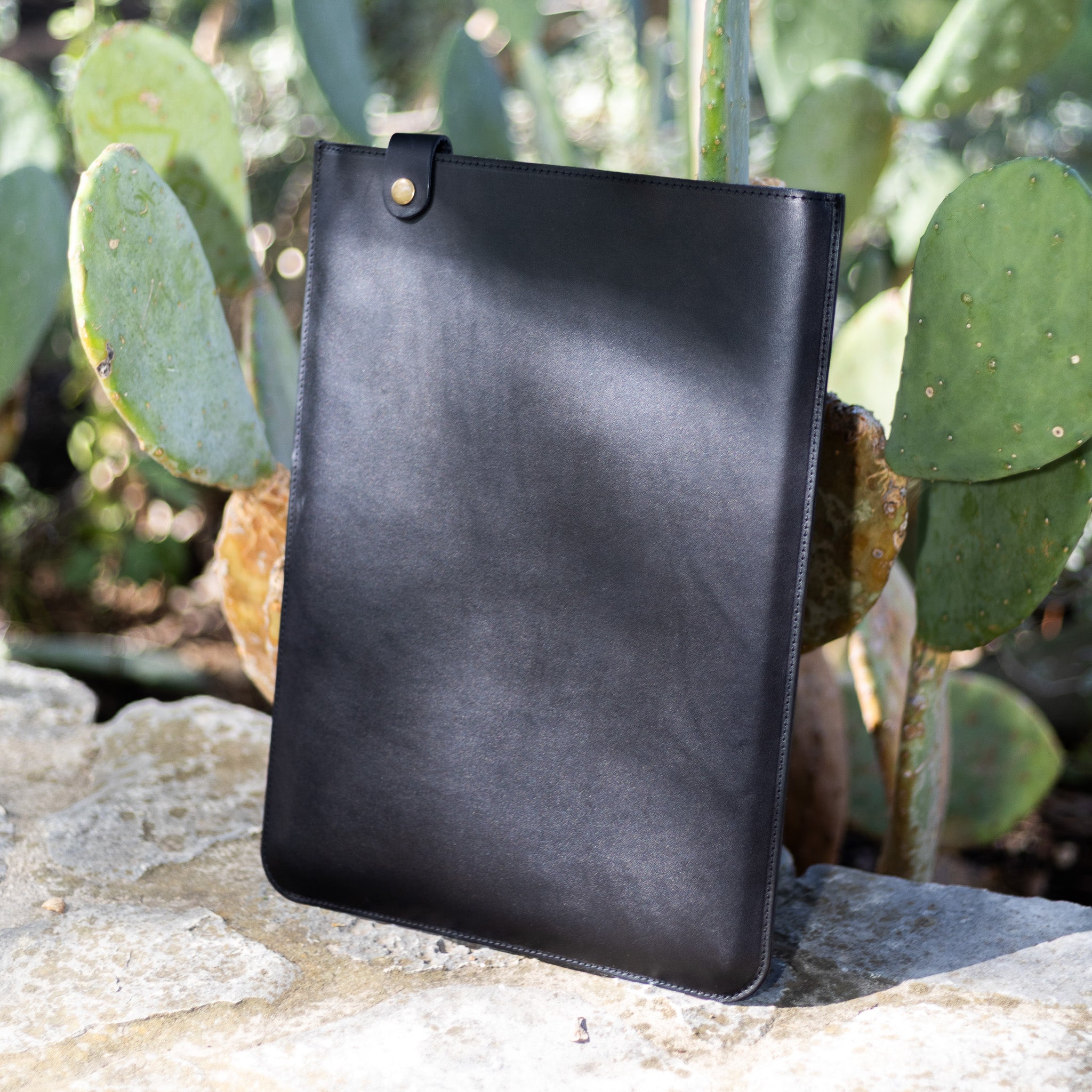 Black vertical leather MacBook sleeve, three-quarter view