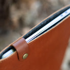 MacBook seated in a wool-lined leather sleeve with the snap tab open