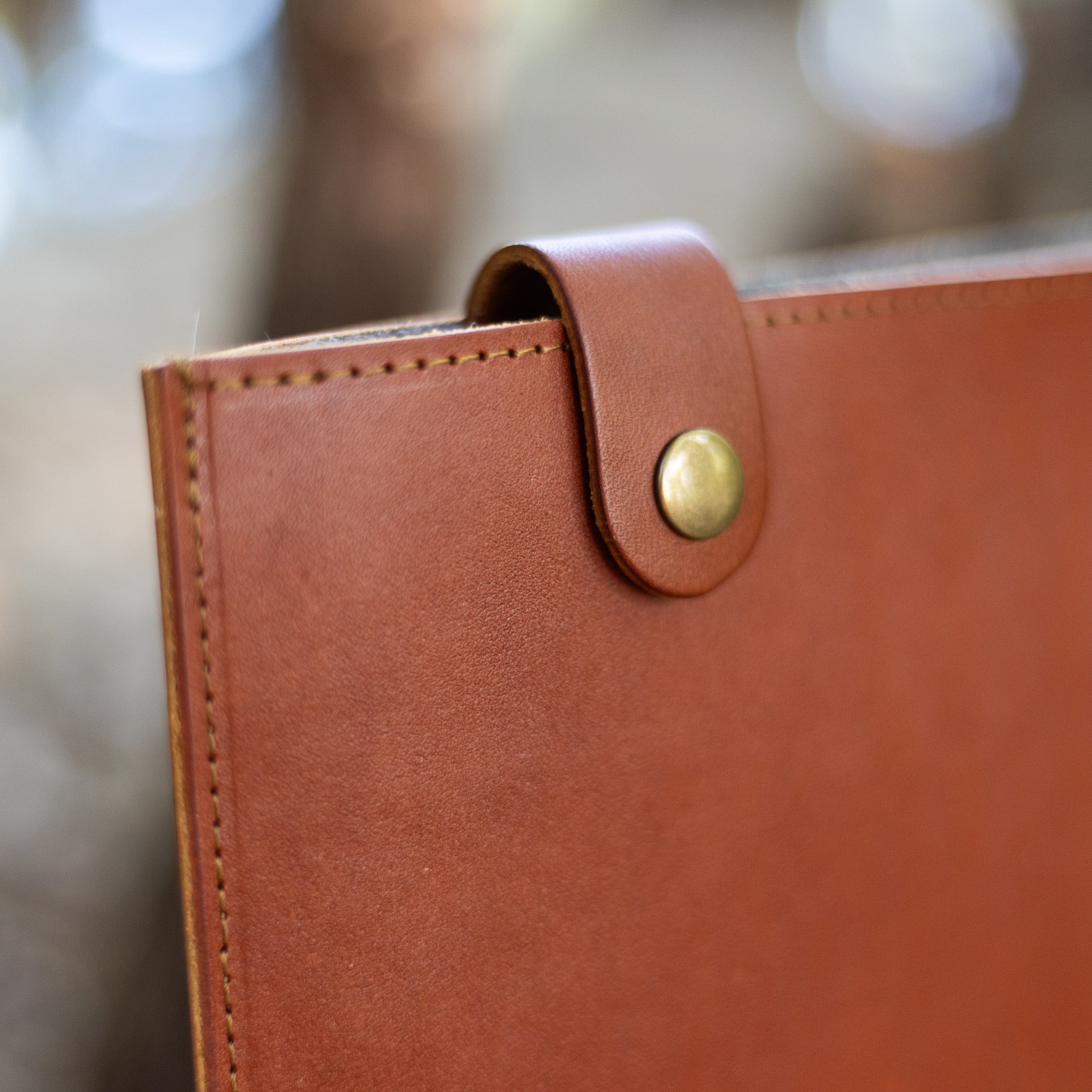 Brass snap and leather closure tab on a Chestnut leather MacBook sleeve