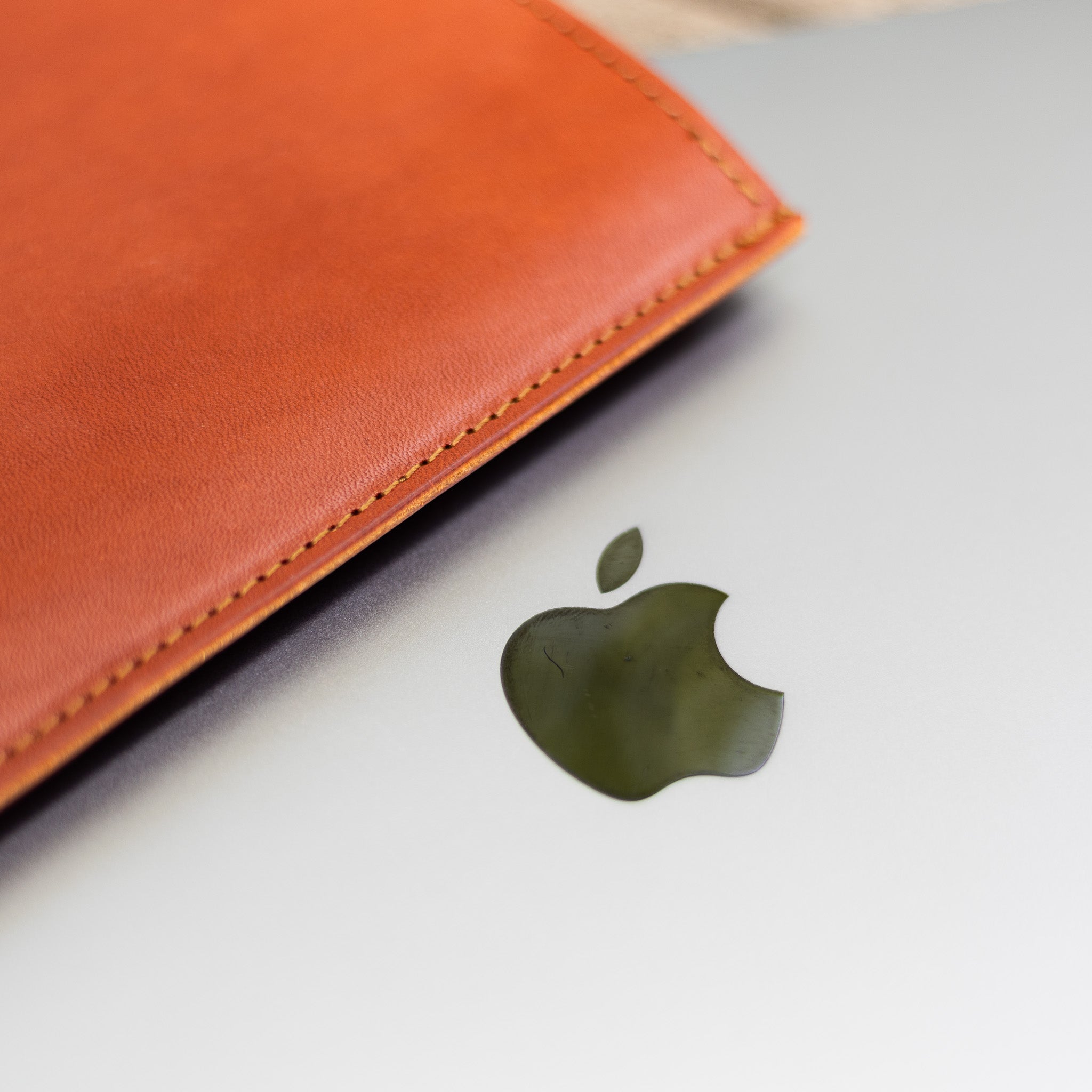 Stitched edge of an English Bridle leather laptop sleeve over a MacBook