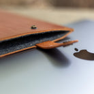 Charcoal wool felt lining inside a leather MacBook sleeve
