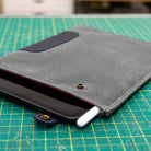 Blue iPad Sleeve with waxed canvas with a iPad and white stylus on a green cutting mat