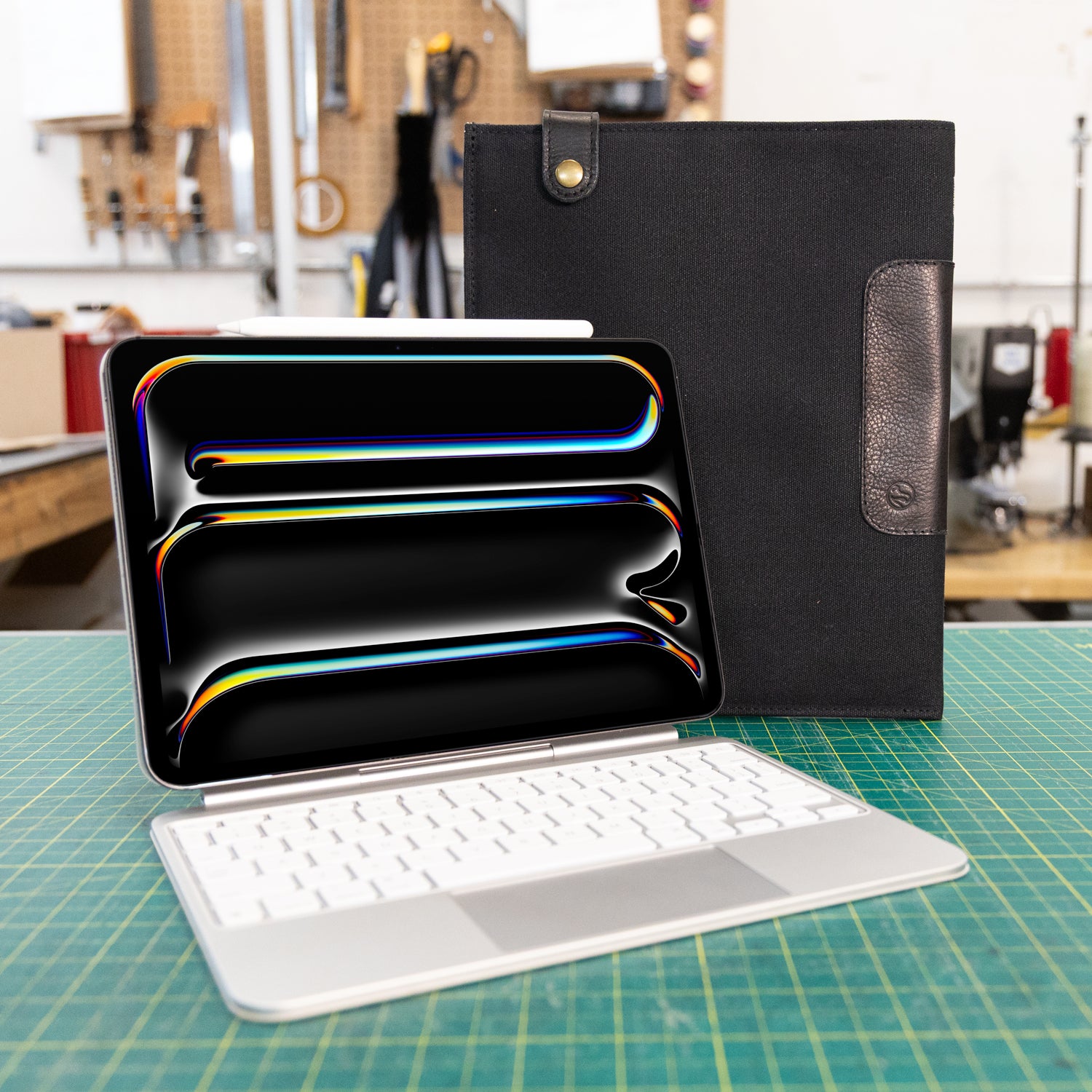 Black iPad keyboard sleeve on a green cutting mat in a workshop setting